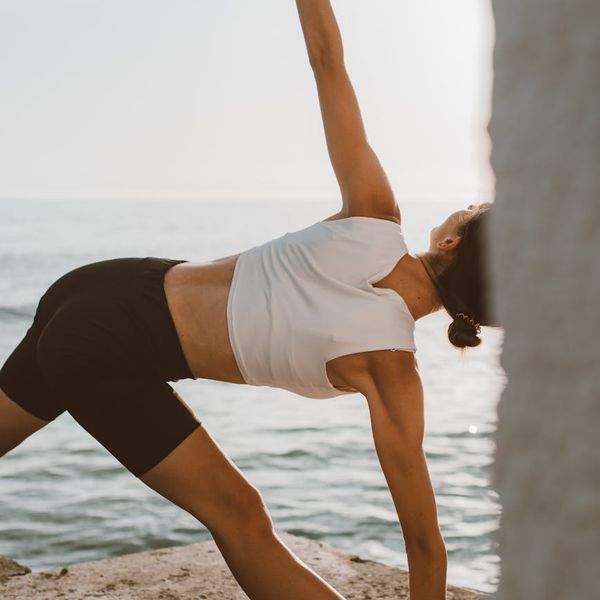Person doing a powerful warrior yoga pose at sunrise.